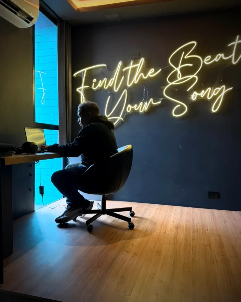 Estiduar Castro produciendo en su estudio bajo el neón Find the Beat of Your Song