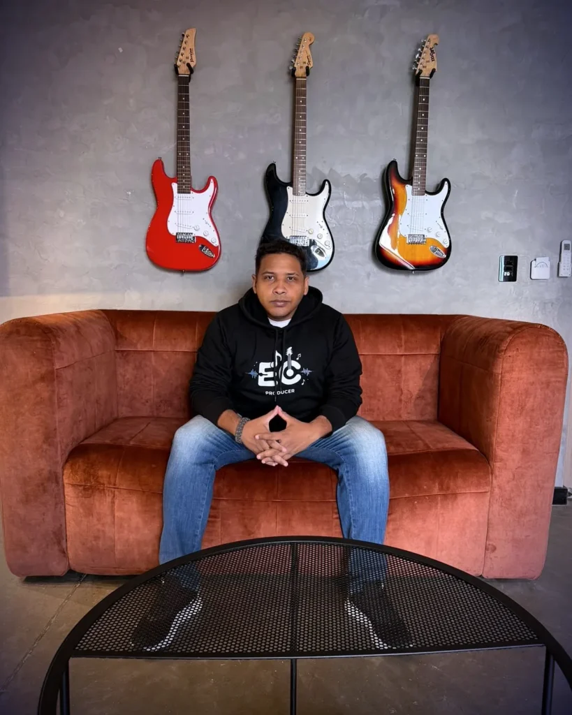 Estiduar Castro on a red couch in front of three guitars